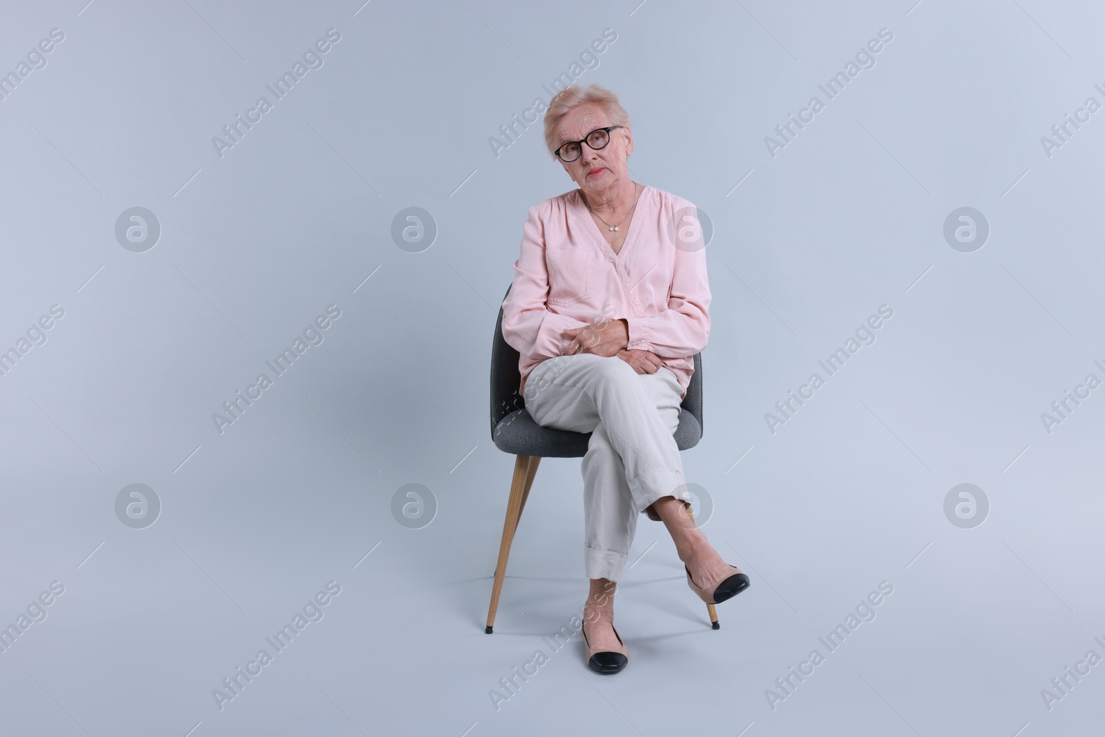 Photo of Senior woman on chair against light background