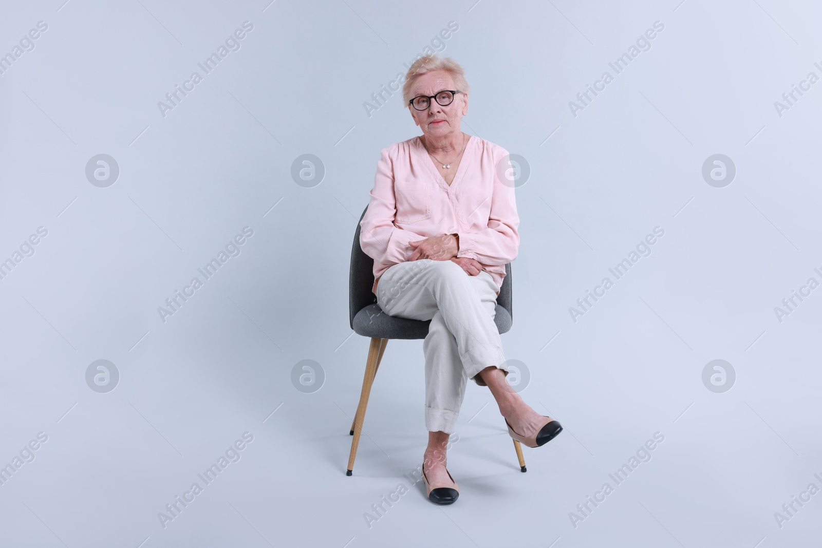 Photo of Senior woman on chair against light background