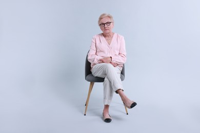 Photo of Senior woman on chair against light background