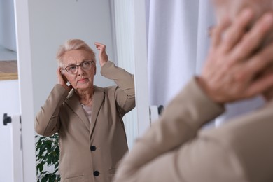 Photo of Beautiful senior woman near mirror at home