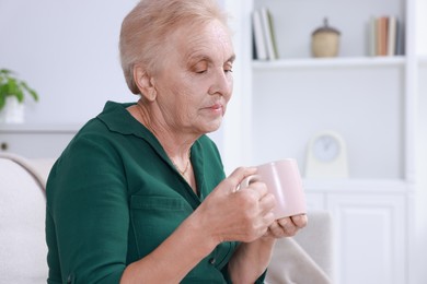 Photo of Senior woman with cup of hot drink at home. Space for text