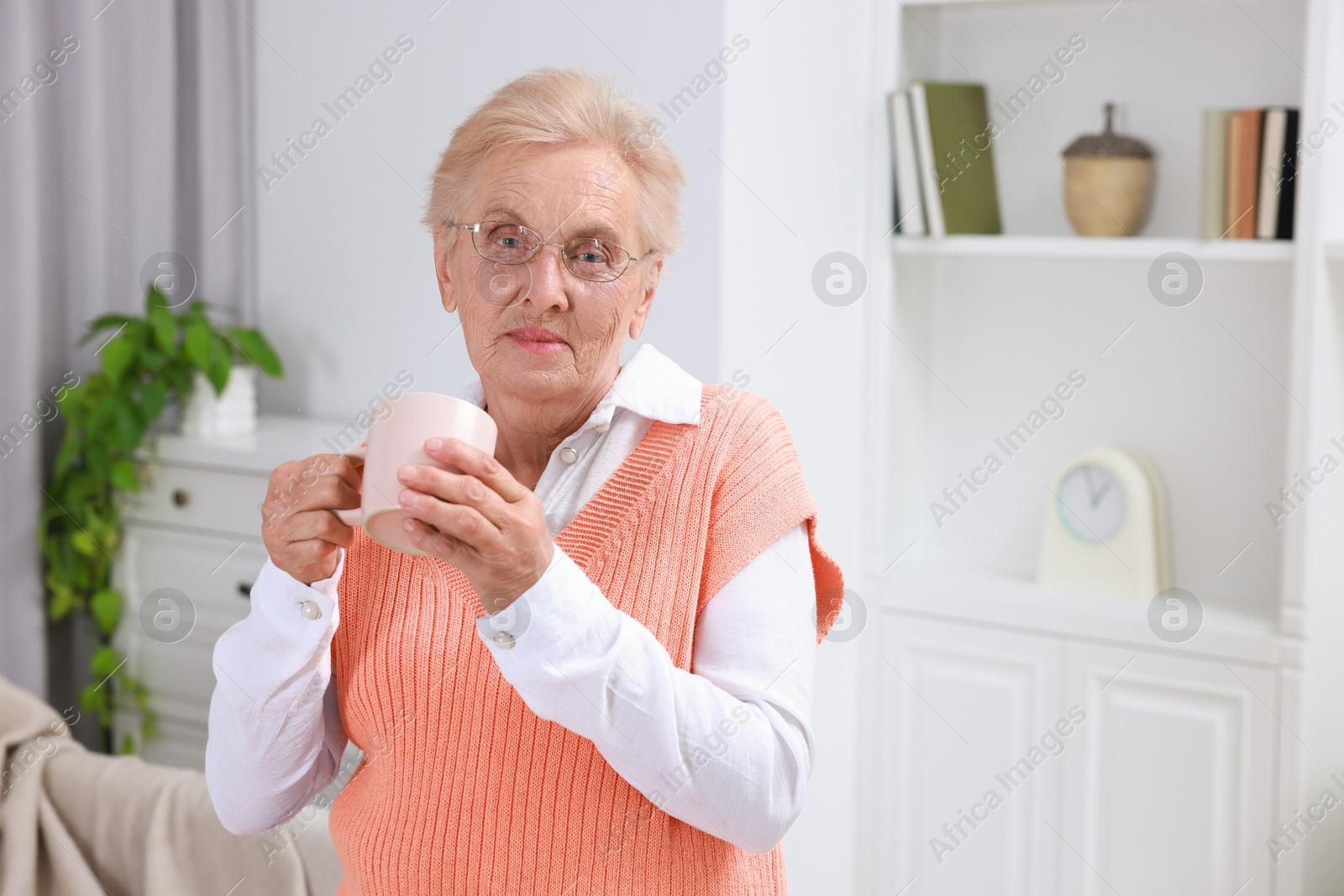 Photo of Senior woman with cup of drink at home. Space for text