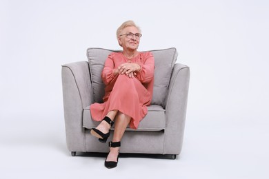 Photo of Senior woman in armchair against white background