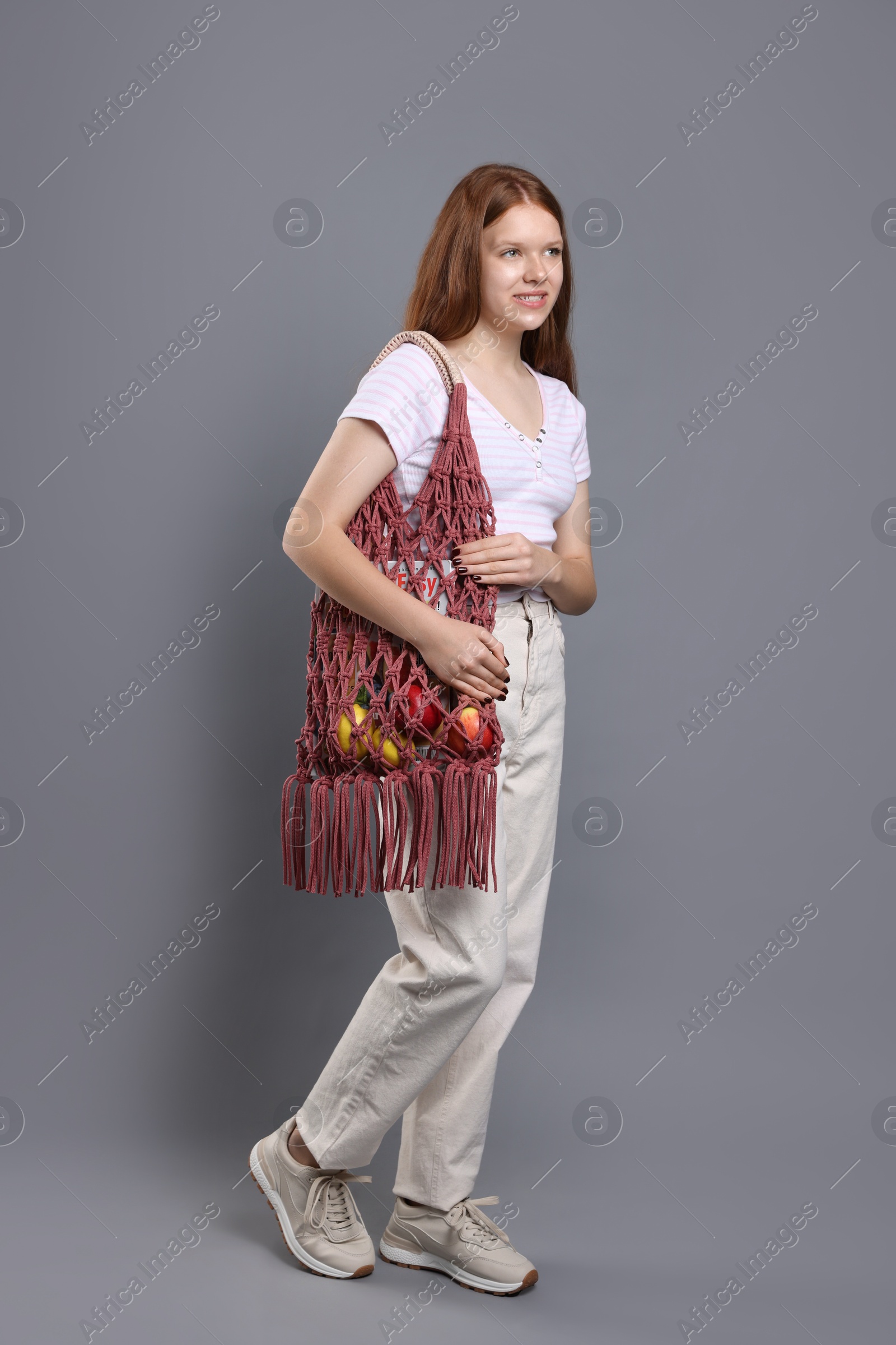 Photo of Teenage girl with handmade macrame bag on grey background