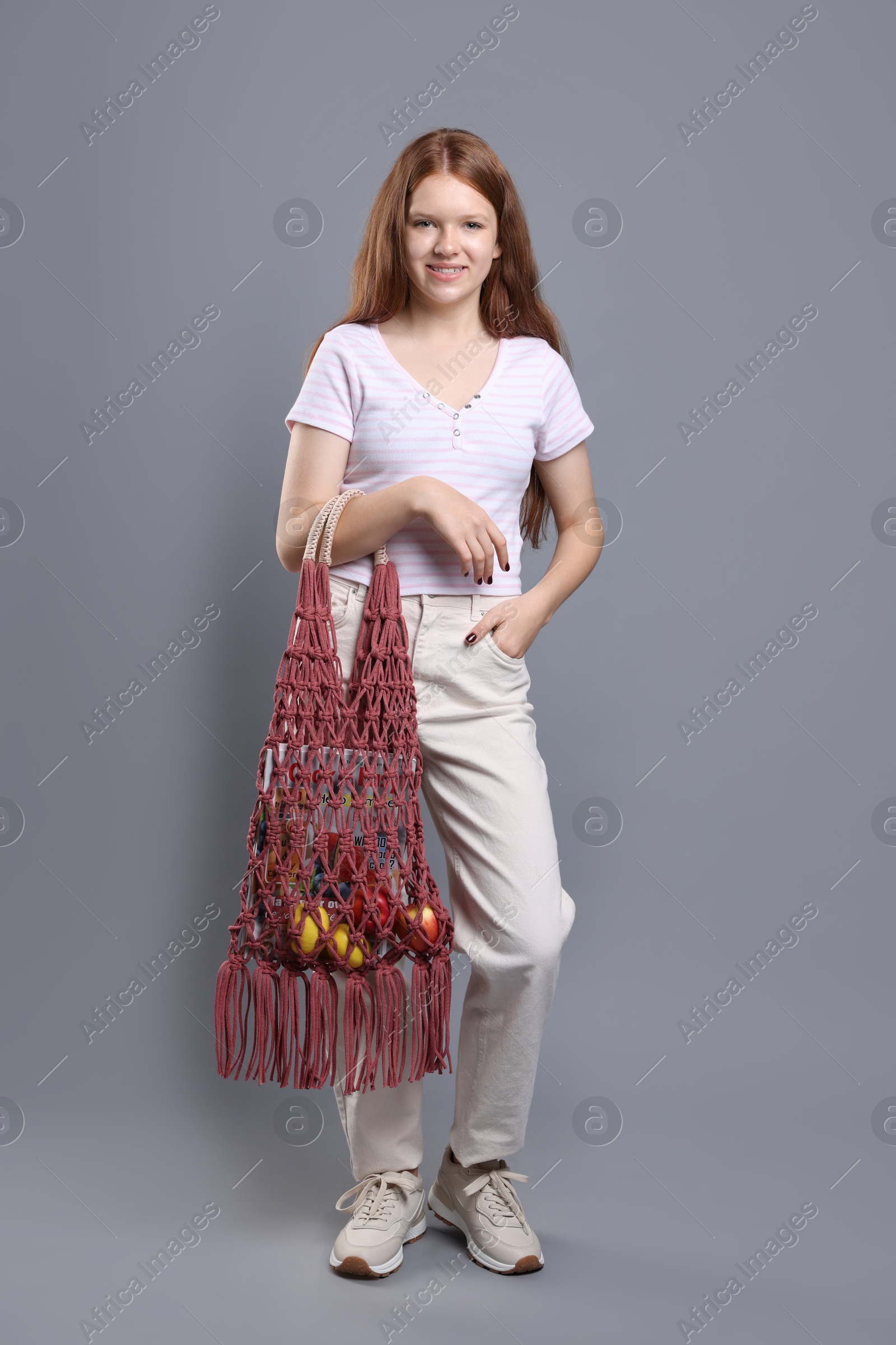 Photo of Teenage girl with handmade macrame bag on grey background