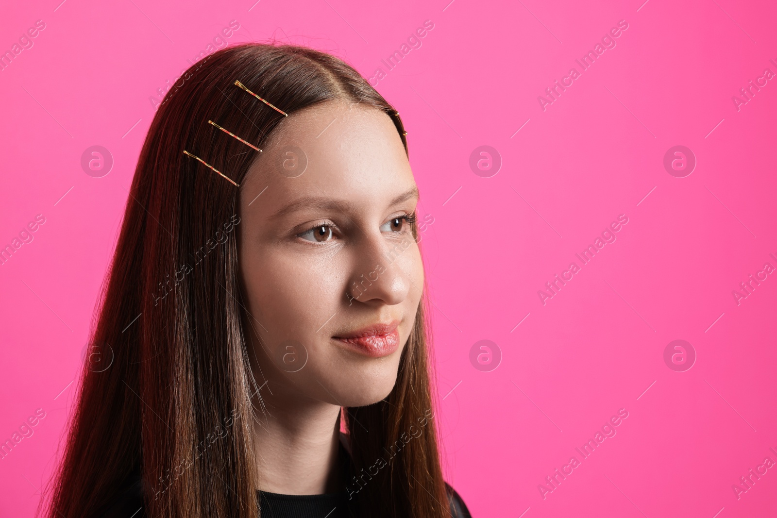 Photo of Teenage girl with stylish hair clips on pink background, space for text