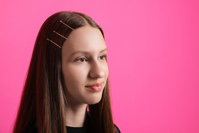 Photo of Teenage girl with stylish hair clips on pink background, space for text