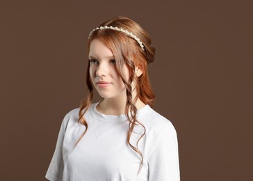 Teenage girl with stylish hair accessory on brown background. Space for text