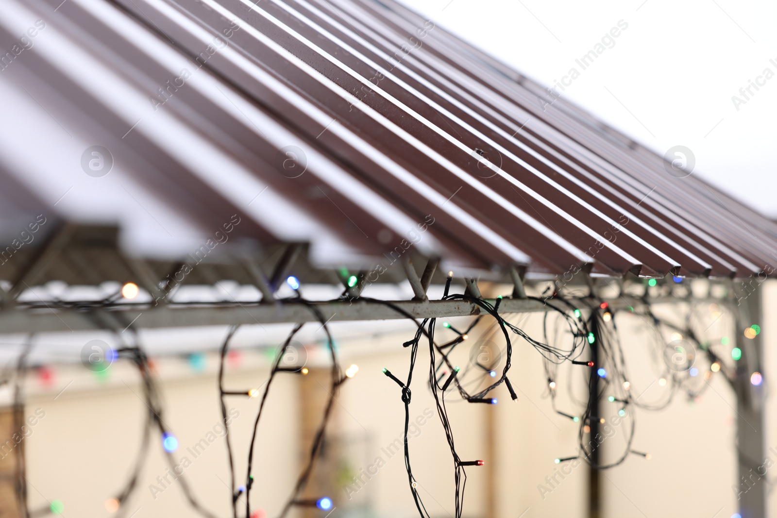 Photo of Roof of house decorated with Christmas lights outdoors, closeup