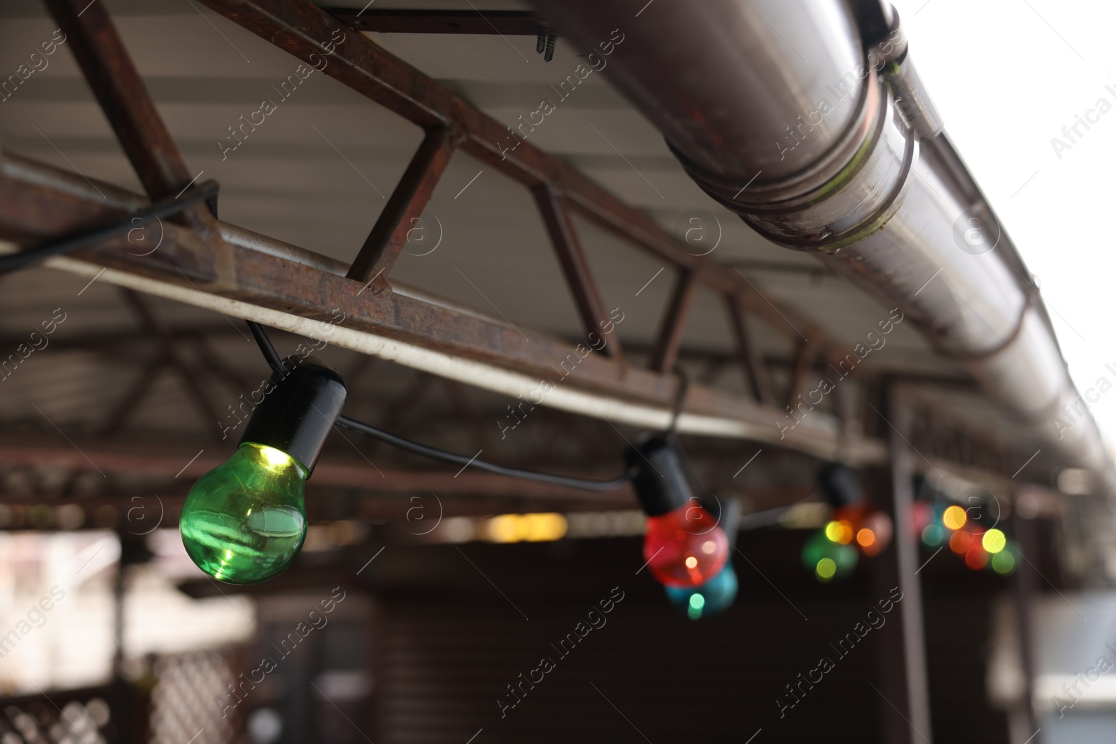 Photo of Christmas celebration. Canopy decorated with colorful light bulbs outdoors, closeup. Space for text