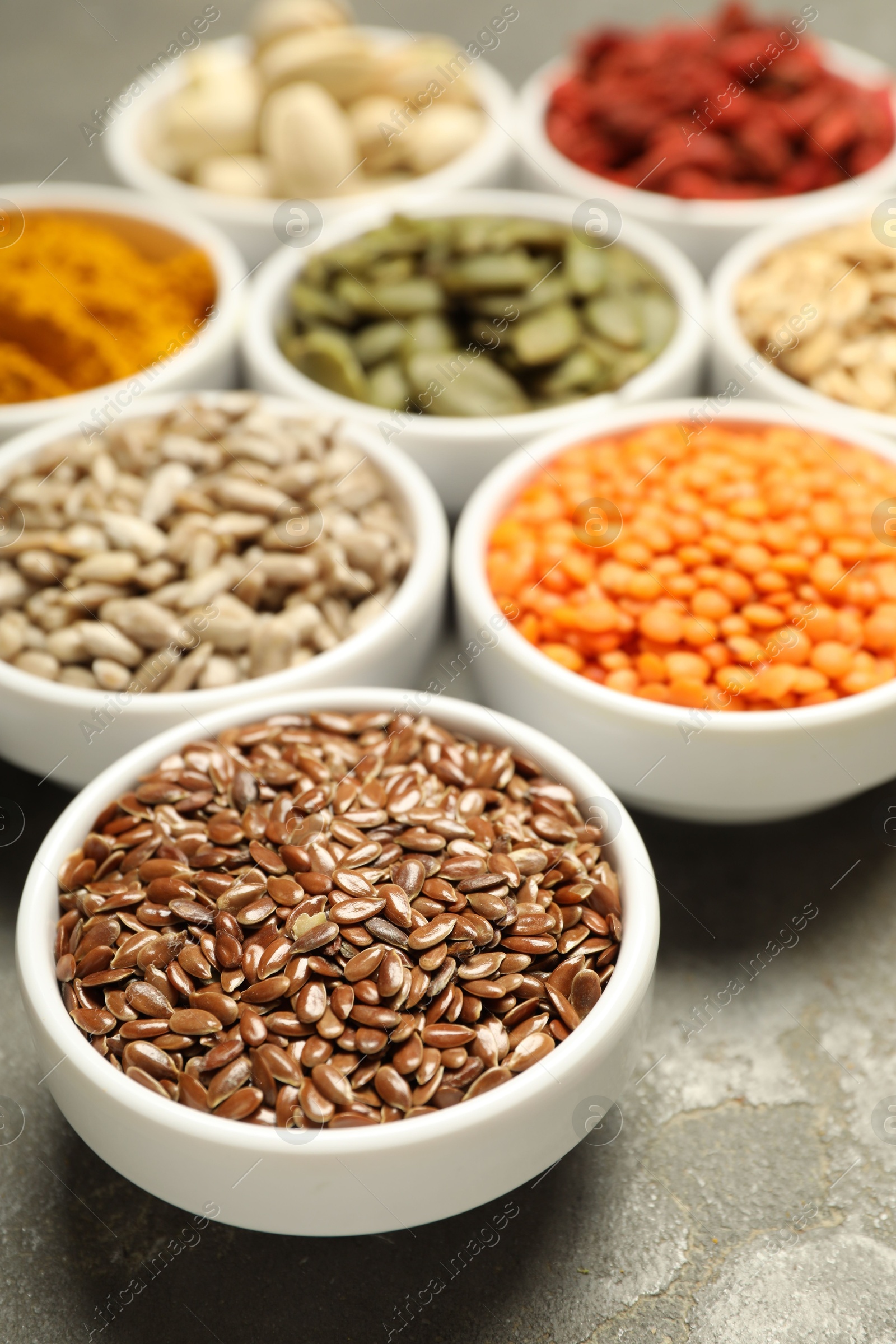 Photo of Different superfoods in bowls on grey table, closeup