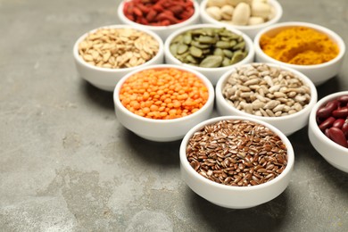 Photo of Different superfoods in bowls on grey table, closeup. Space for text