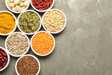 Photo of Different superfoods in bowls on grey table, flat lay. Space for text