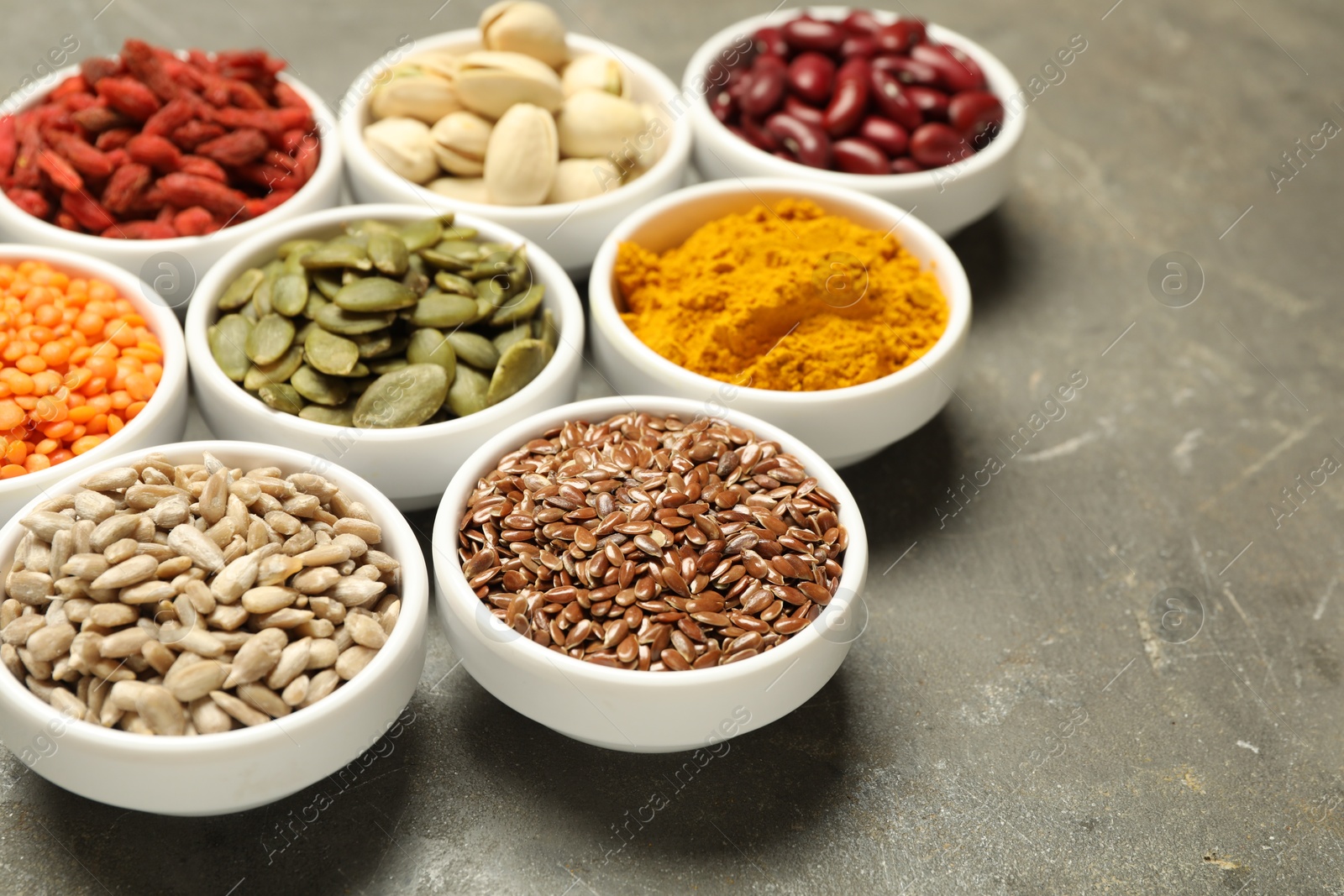 Photo of Different superfoods in bowls on grey table, closeup