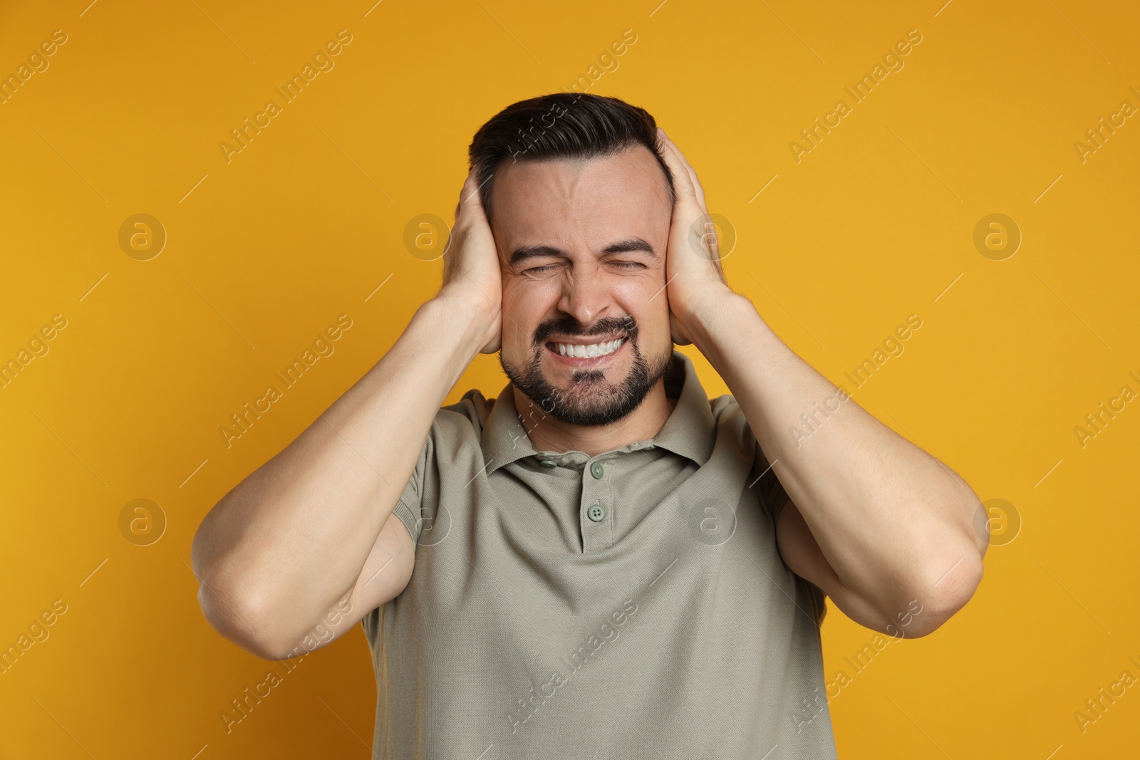 Photo of Man covering his ears on orange background