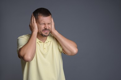 Photo of Man covering his ears on grey background, space for text