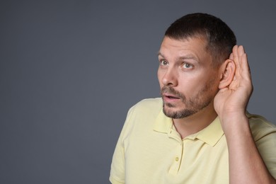 Photo of Man showing hand to ear gesture on grey background, space for text