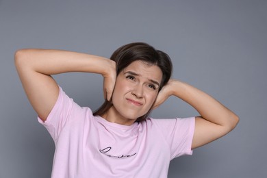 Woman covering her ears on grey background