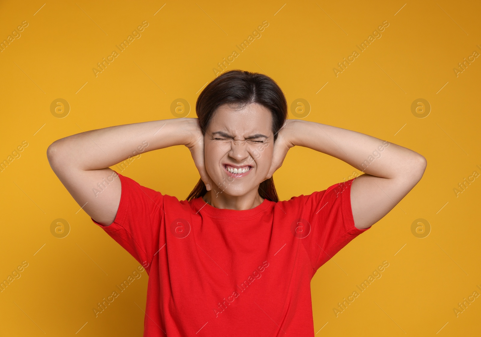 Photo of Woman covering her ears on orange background