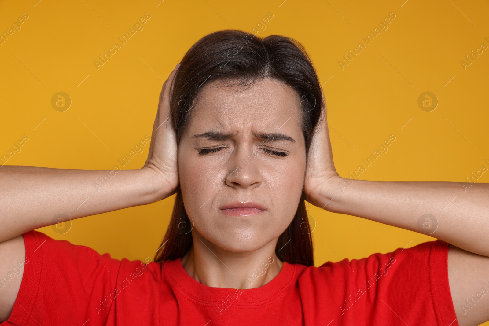 Photo of Woman covering her ears on orange background