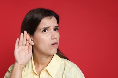 Woman showing hand to ear gesture on red background, space for text