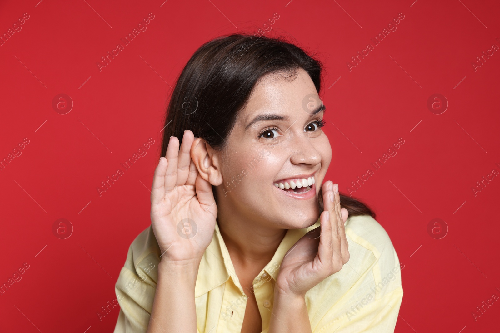 Photo of Woman showing hand to ear gesture on red background