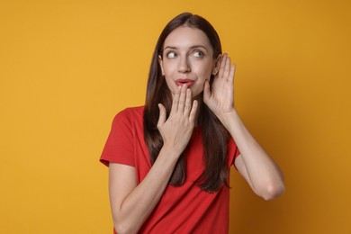 Photo of Woman showing hand to ear gesture on orange background