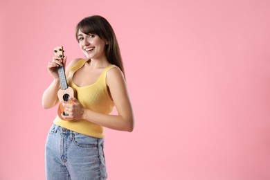 Photo of Happy woman playing ukulele on pink background, space for text