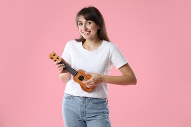 Photo of Happy woman playing ukulele on pink background