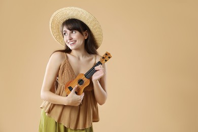 Happy woman playing ukulele on beige background, space for text