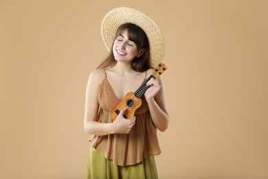 Happy woman playing ukulele on beige background