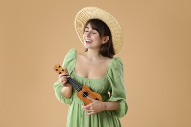 Happy woman playing ukulele on beige background