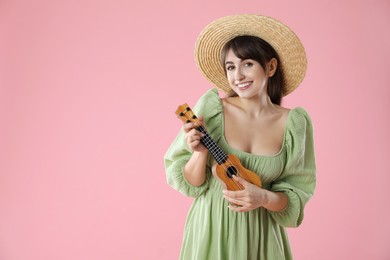 Happy woman playing ukulele on pink background, space for text