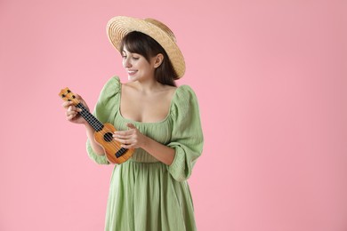 Happy woman playing ukulele on pink background