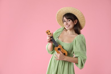 Photo of Happy woman playing ukulele on pink background, space for text