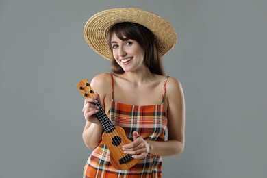 Photo of Happy woman playing ukulele on grey background