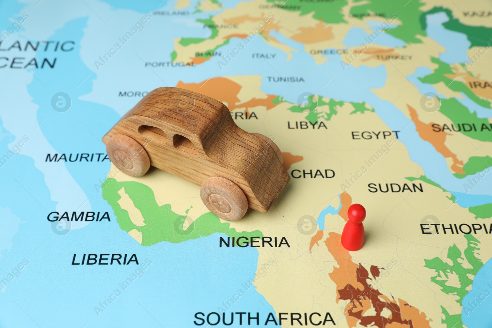 Photo of Wooden toy car and red human figure on world map. Road trip