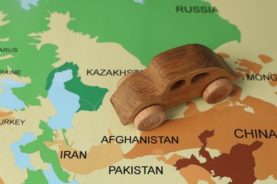 Photo of Wooden toy car on world map, closeup. Road trip