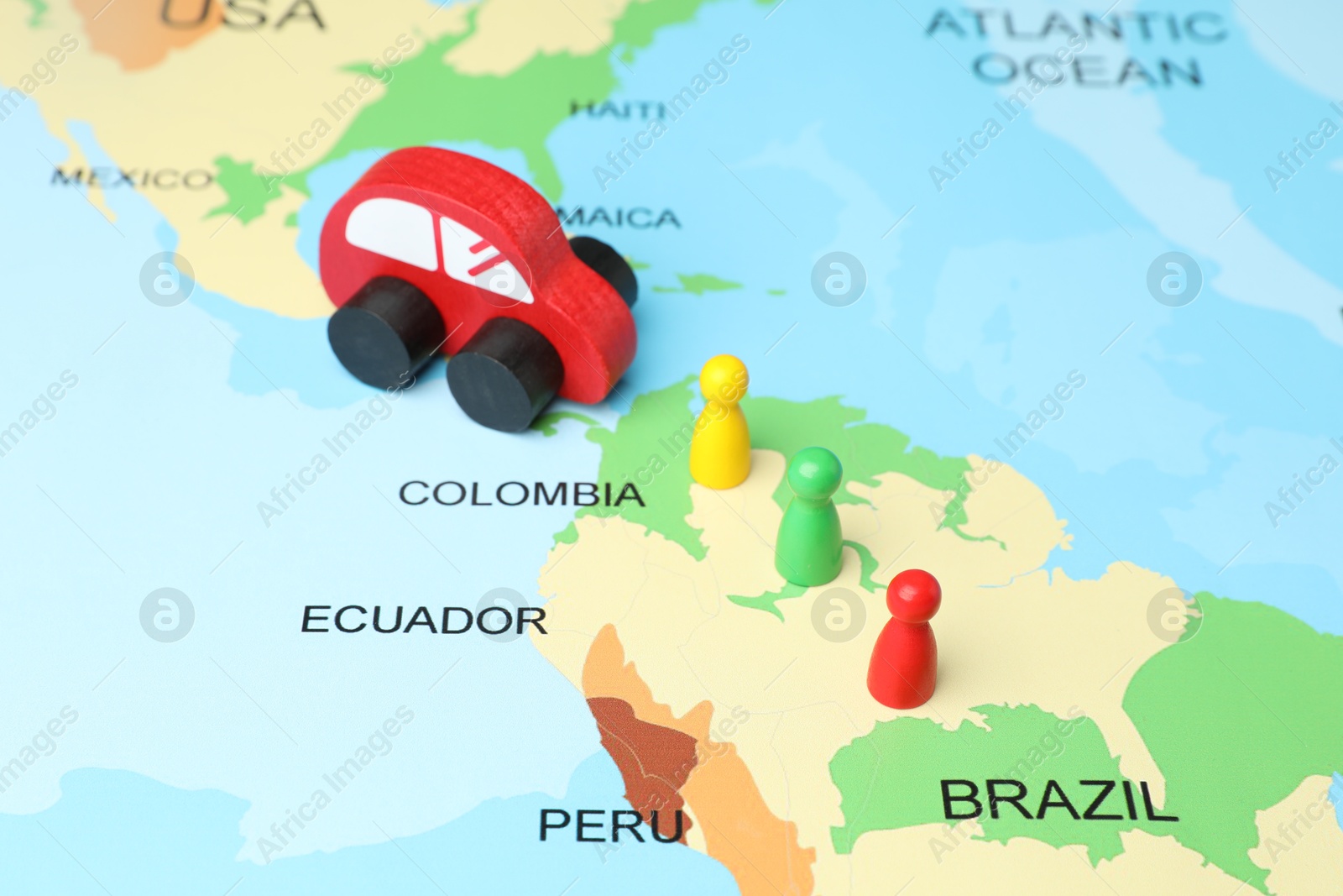 Photo of Red wooden toy car and human figures on world map. Road trip planning