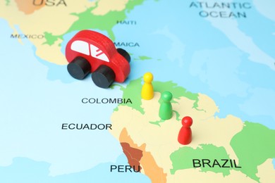 Photo of Red wooden toy car and human figures on world map. Road trip planning