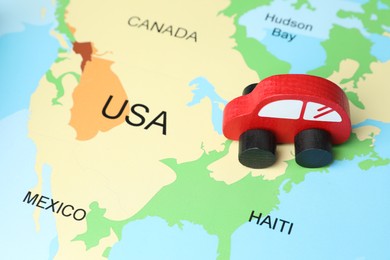 Photo of Red wooden toy car on world map. Road trip