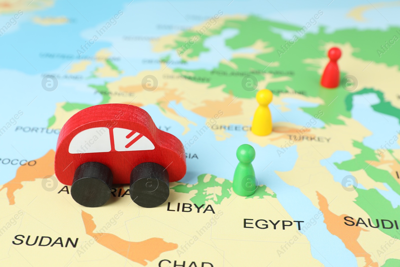 Photo of Red wooden toy car and human figures on world map. Road trip planning