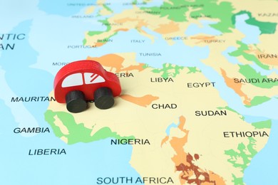 Photo of Red wooden toy car on world map. Road trip