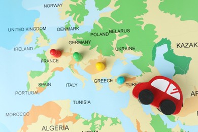 Photo of Red wooden toy car and human figures on world map, flat lay. Road trip planning