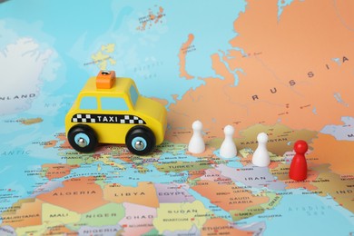 Photo of Yellow taxi car and human figures on world map. Road trip planning