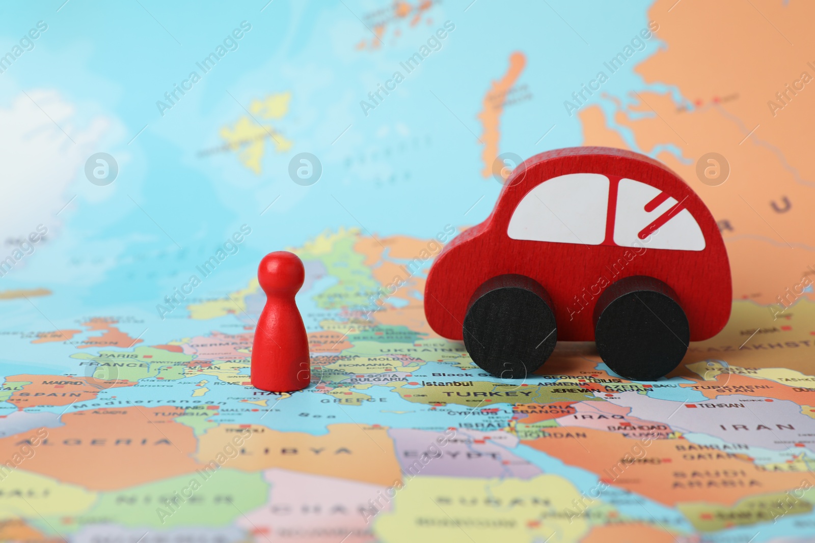 Photo of Red wooden toy car and human figure on world map. Road trip