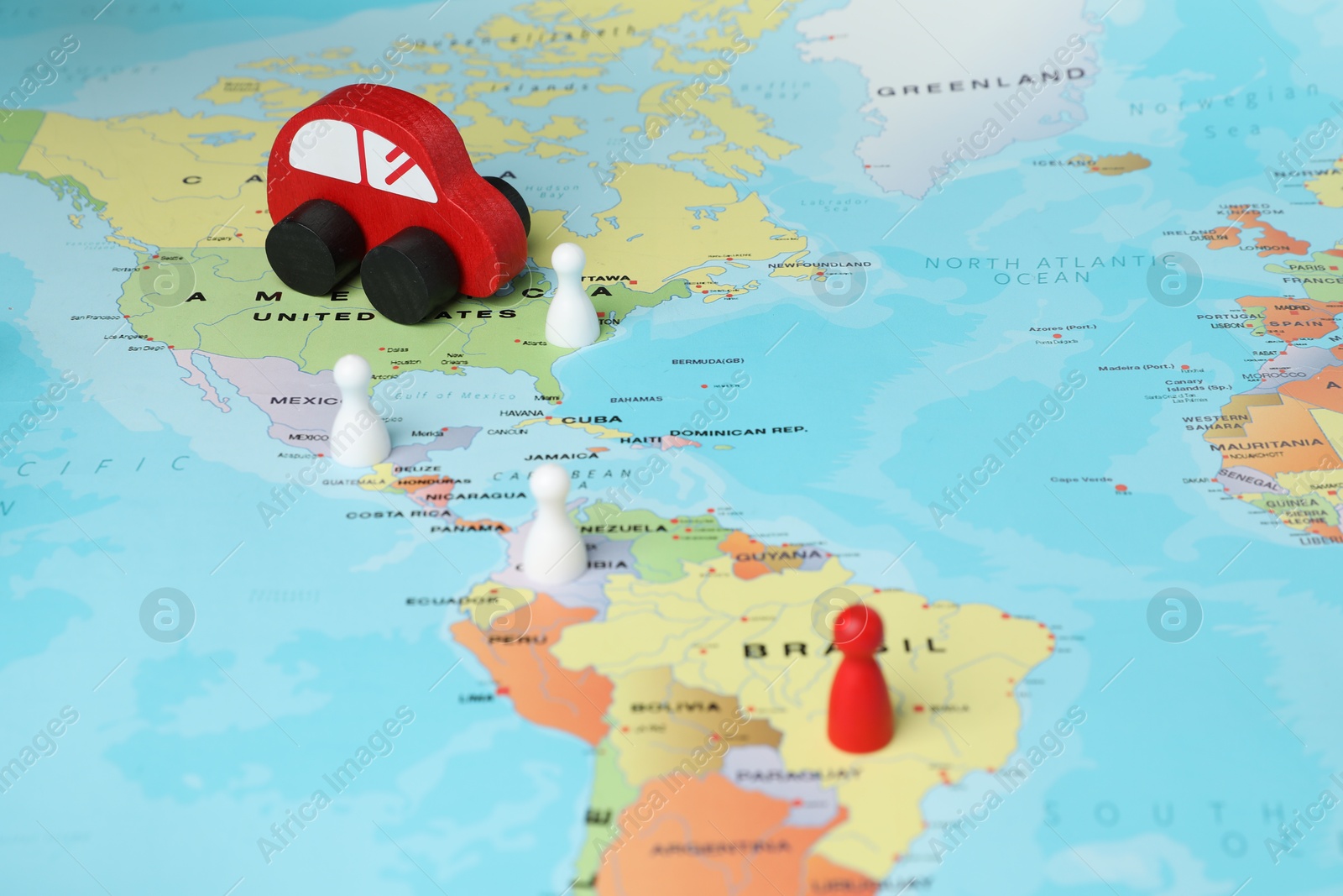 Photo of Red wooden toy car and human figures on world map. Road trip planning