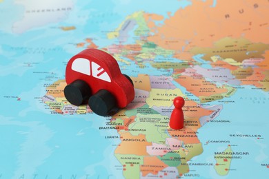 Photo of Red wooden toy car and human figure on world map. Road trip