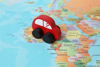 Photo of Red wooden toy car on world map. Road trip