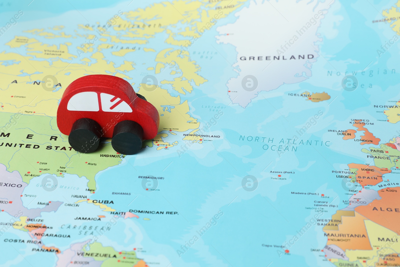 Photo of Red wooden toy car on world map. Road trip